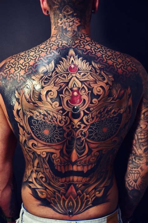 The Back Of A Man With Tattoos On His Body And Chest Is Covered In