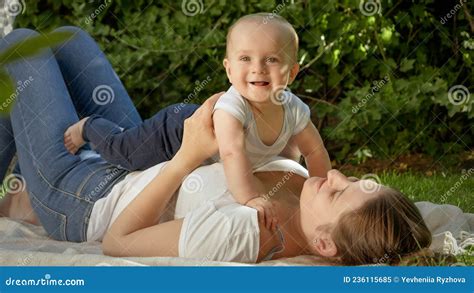 Portrait Of Happy Smiling Mother Lying On Grass And Palying With Her