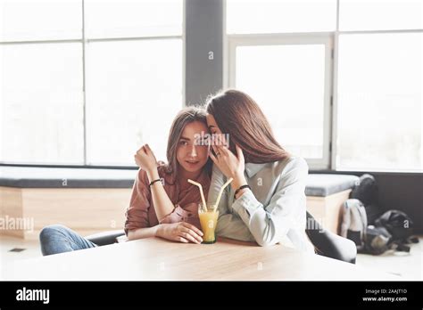 Two Beautiful Twin Girls Spend Time Drinking Juice Sisters Relaxing In A Cafe And Having Fun