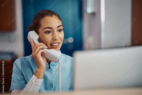 Young Nurse Answering Phone Call While Working On Desktop Pc At