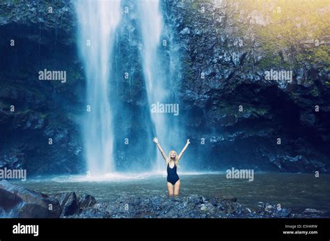 Woman Enjoying Pool At The Base Of Large Waterfall In Hawaii Stock
