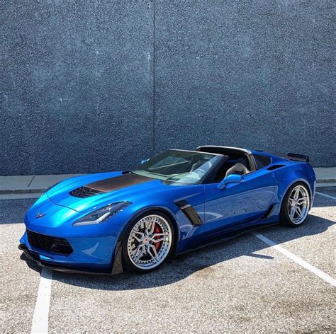 A Blue Sports Car Parked In A Parking Lot Next To A Concrete Wall With
