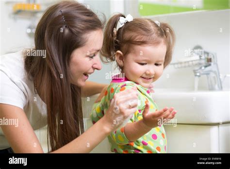 Smiling Girl Child And Her Mother Washing Hands And Face With Soap In