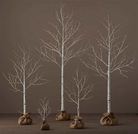 Four White Trees With Brown Bags In Front Of Them