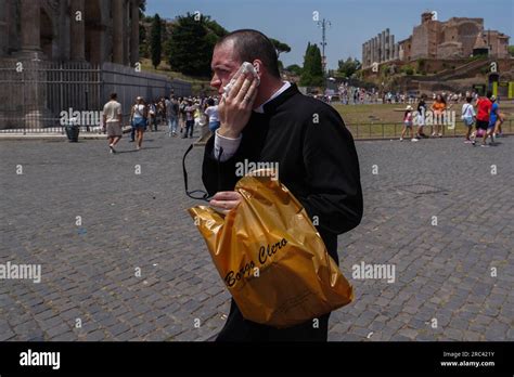Rome, Italy. 12 July 2023 A priest wipes the sweat from his face as