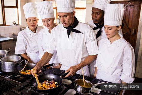 Head Chef Teaching His Team To Prepare A Food In Kitchen S Years Stock Photo