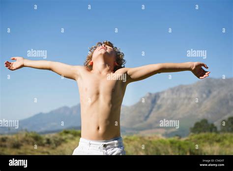 Shirtless Little Boy Standing With His Eyes Closed And Arms