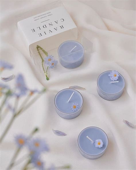 Four Blue Candles Sitting On Top Of A White Sheet Next To Flowers And A