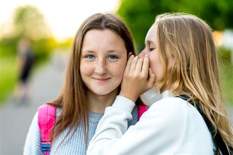 Two Girl Friends Schoolgirl In The Summer In City Tells A Friend In The Ear A Secret Really