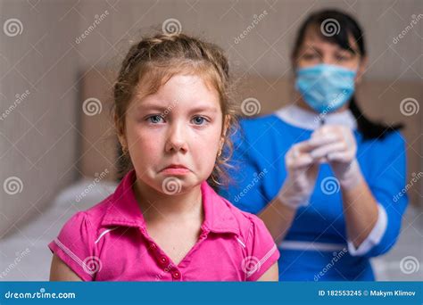Portrait Of A Sad Child On The Background Of A Nurse In A Medical Mask