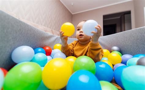 Pequeño Bebé Lindo Jugando Con Bolas De Colores En La Piscina Seca