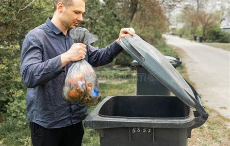 Man Throwing Out Black Eco Friendly Recyclable Trash Bag In To Big