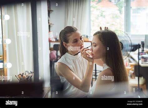 Positive Young Female Makeup Artist Doing Clients Face Makeup Using