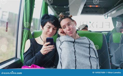 Two Lesbians Sitting In A Tourist Bus Looking At The Screen Of A