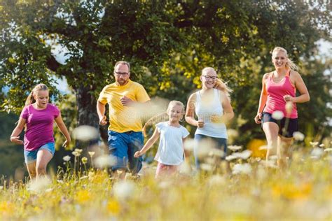 Familia Que Corre En Un Prado Para El Deporte Imagen De Archivo