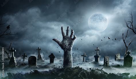 Zombie Hand Rising Out Of A Graveyard In Spooky Night Stock Photo