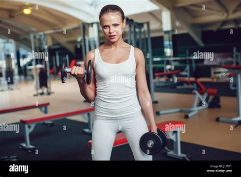 hermosa chica haciendo ejercicios con pesas en el gimnasio vestido blanco cima depósito y