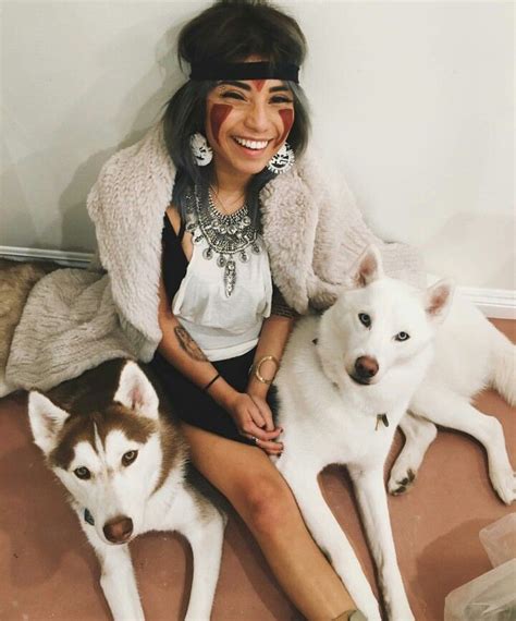 A Woman Sitting On The Floor With Two Husky Dogs And One Is Smiling At
