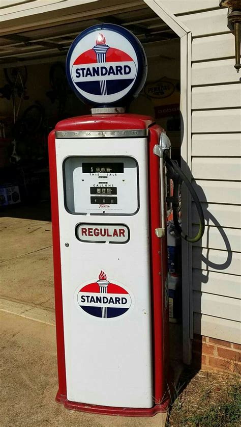 An Old Fashioned Gas Pump Sitting In Front Of A Garage