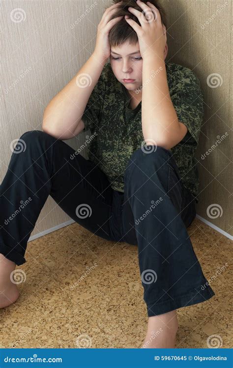 Boy Teenager With Depression Sitting In The Corner Of Room Stock Photo