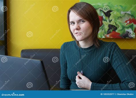 a girl with a pensive tense expression on her face sits working at a laptop at a table in a