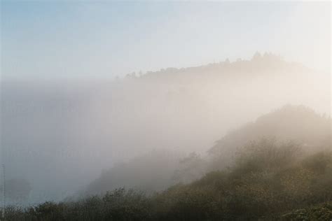 Sun Burning Up Thick Fog Over Hills At Sunset By Stocksy Contributor