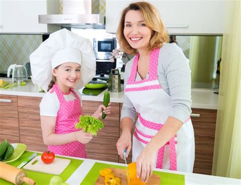 Retrato De Feliz Joven Madre Con Hija En Delantal Rosa Cocinando En La
