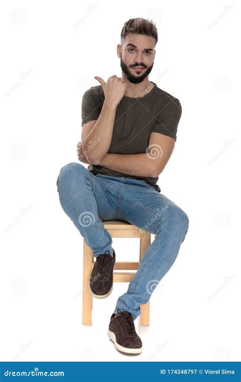 Arrogant Casual Man Pointing Behind Him While Sitting Stock Image
