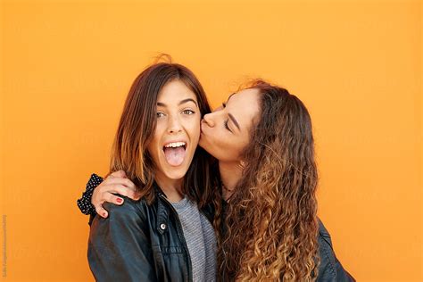Girl Sticking Out Tongue While Girlfriend Kissing Her By Stocksy Contributor Guille Faingold