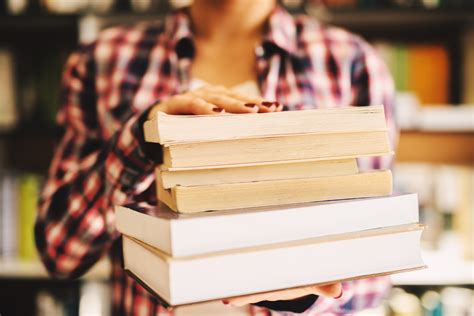 Close Up Of Females Hands Holding Books In Front Of The Camera