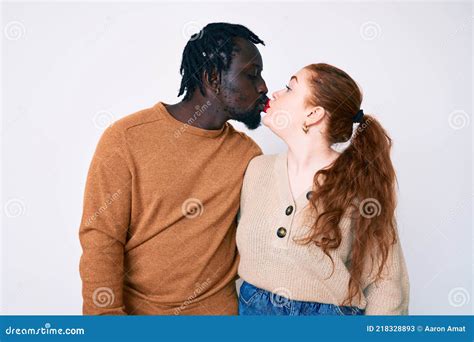 Interracial Couple Wearing Casual Clothes Looking At The Camera Blowing