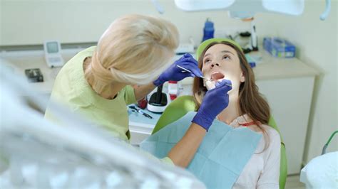 Dental hygienist examining patient teeth with mouth mirror and probe ...