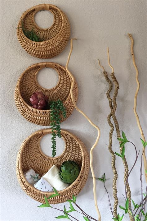 Three Wicker Baskets Hanging On The Wall With Plants And Soaps In Them