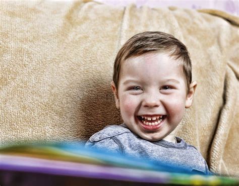 Little Happy Boy Laughing While Sitting On The Couch Close Up Stock