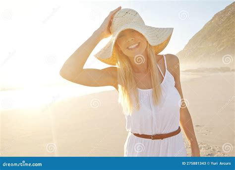 Beauty In The Sunlight A Gorgeous Young Woman Wearing A White Dress And Sunhat On The Beach