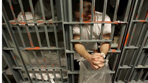 An Inmate Leans Out The Bars Of His Cell In A One Prisoner Per Cell