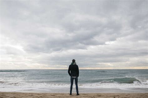 Back View Of Man Standing On The Beach In Winter Looking At Distance
