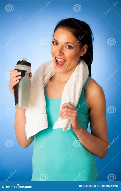 Woman Rests After Fitness Workout With Towel Around Her Neck Drinking