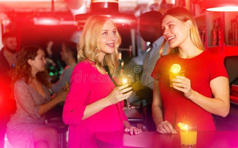 Two Young Women With Cocktails Having Fun On Party At Nightclub Stock