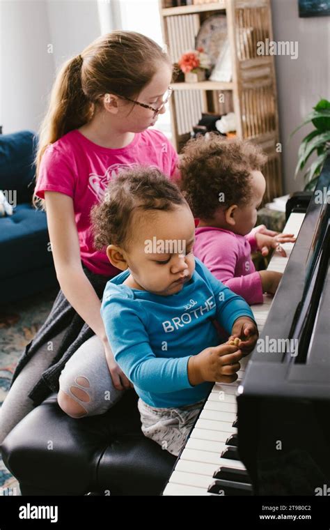 Multiracial Twin Toddlers And Tween Girl Play Piano Together Stock