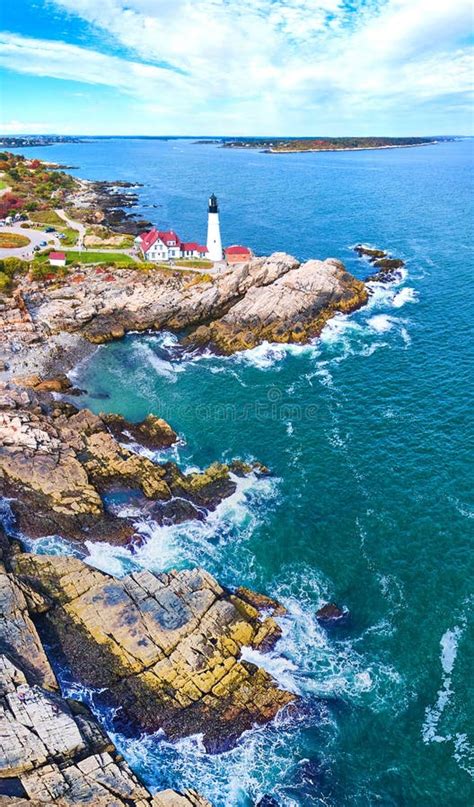 Ocean Waves Crash Into Rocky Maine Coast With Large Lighthouse On Edge