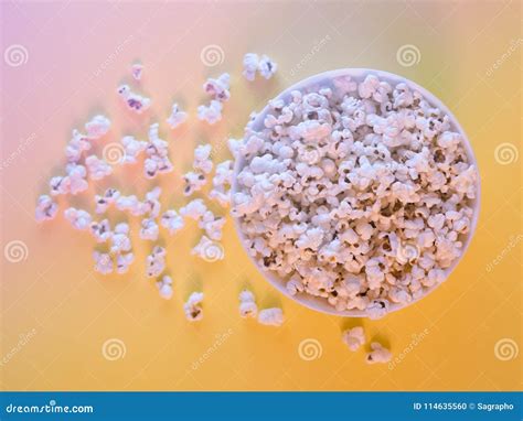 Popcorn In The White Bowl Spilled On A Yellow Surface Stock Photo