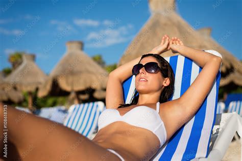 Relaxed Woman Sunbathing And Relaxing Lying On Deck Chair At Tropical