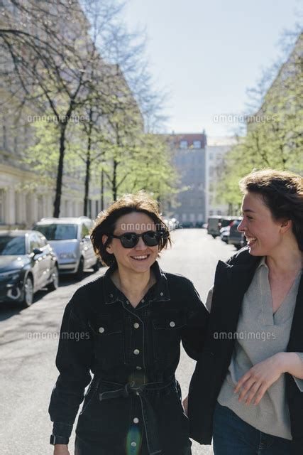 Cheerful Lesbian Couple Walking On Street In City During Sunny Day 11081047592 の写真素材・イラスト素材｜アマナイメージズ