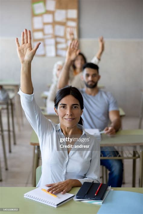 Group Of Students Raising Their Hands To Ask Questions To The Teacher