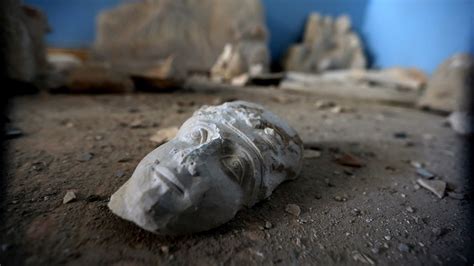 The Face Of A Statue Lies On The Ground At The Destroyed Museum In The Ancient Syrian City Of