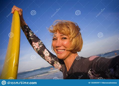 Young Attractive And Happy Blonde Surfer Woman In Swimsuit Holding Surf