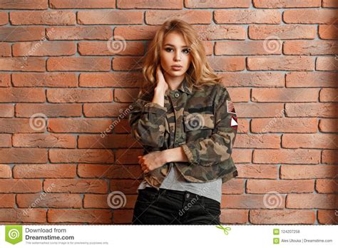 Beautiful Young Girl In Military Jacket Near Red Brick Wall Stock