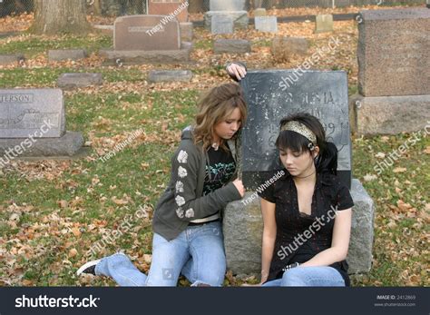 Sad Blonde And Brunette Teen Girls Sitting In Graveyard