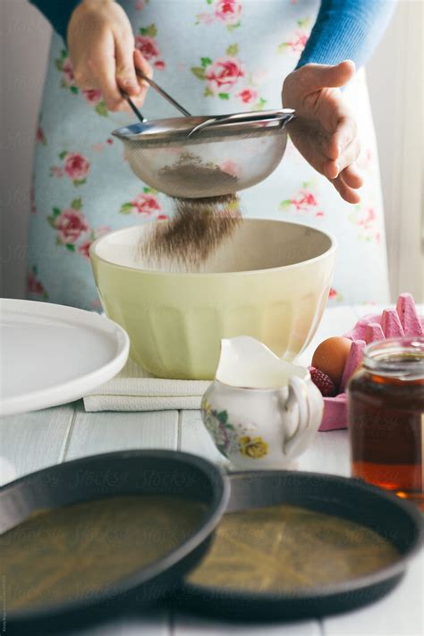Woman Sifting Cocoa Into Mixing Bowl To Make Chocolate Cake By Stocksy Contributor Kirsty